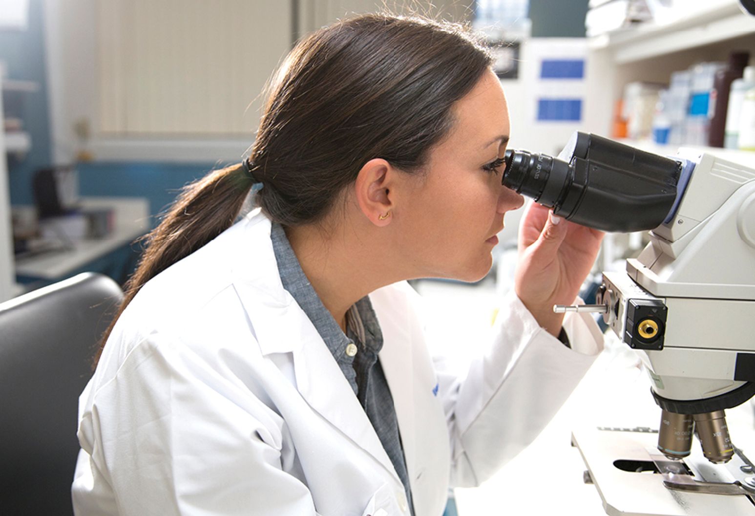 female physician looking into microscope